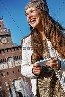 smiling young traveller woman in Milan, Italy writing sms