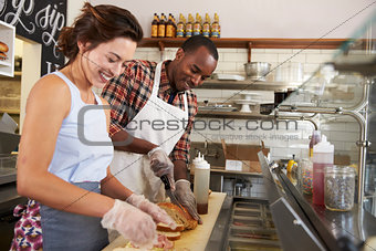 Happy couple working behind the counter at a sandwich bar