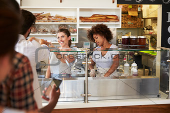 A queue of customers served by two women at a sandwich bar