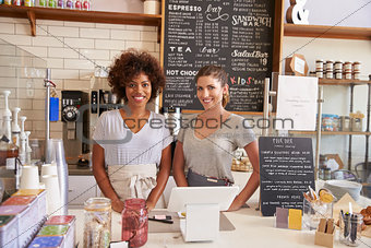 Two women ready to serve behind the counter at a coffee shop