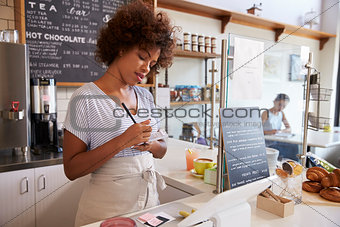Waitress writing down an order at a coffee shop, close up