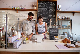 Couple working together at the till in a coffee shop