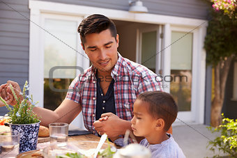 Father And Son Saying Grace Before Outdoor Meal In Garden