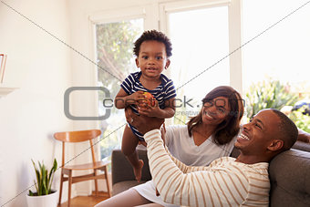 Parents And Son Playing Game On Sofa At Home