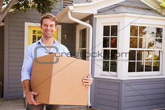 Man Carrying Box Into New Home On Moving Day