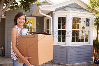 Woman Carrying Box Into New Home On Moving Day