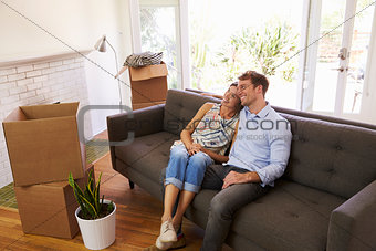 Couple Taking A Break On Sofa During Moving In Day