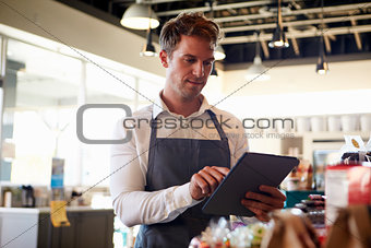 Employee In Delicatessen Checking Stock With Digital Tablet