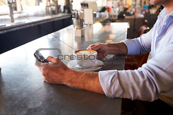 Close Up Of Man Checking Messages On Phone In Coffee Shop