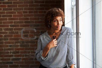 Thoughtful Mature Businesswoman Looking Out Of Office Window