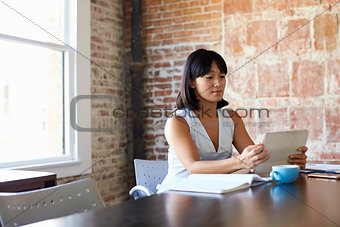 Businesswoman Working On Digital Tablet In Boardroom