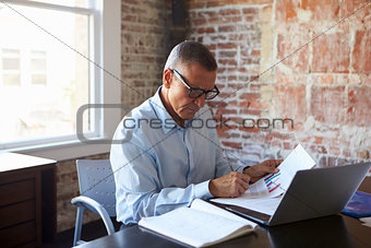 Mature Businessman Working On Laptop In Boardroom