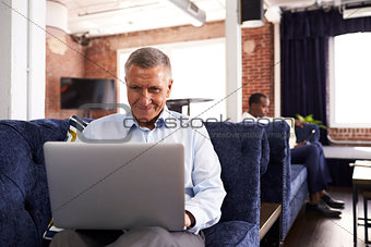 Businessmen Working On Sofas In Relaxation Area Of Office