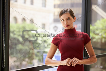 Young white businesswoman leaning by a window at work