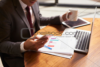 Businessman working on document holding smartphone, close up