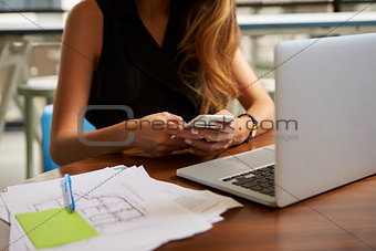 Businesswoman working in office using phone, mid section