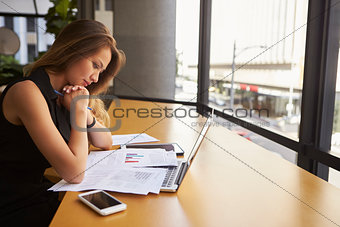 Businesswoman working reading document in office, side view