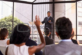 Black businessman giving seminar takes audience questions