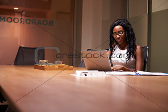 Young black businesswoman working late on laptop in office