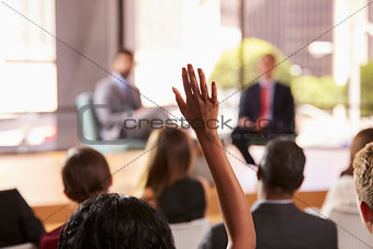Hand in audience raised for a question at a business seminar