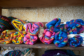 Colourful blankets on shelves in store, close up, front view