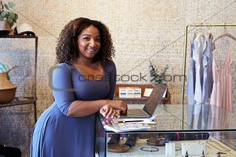 Mixed race woman working in clothes shop looking to camera