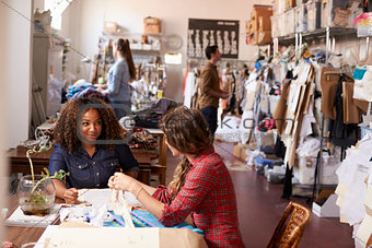 Two women talking at a table in a clothes design studio