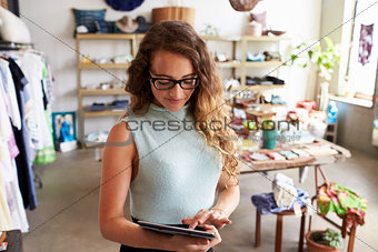 Female business owner using tablet computer in clothes shop