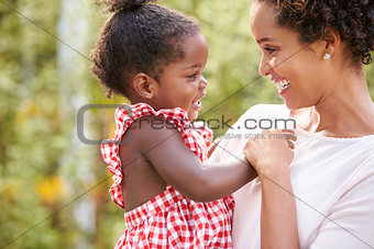 African American mother carries baby daughter and holds hand
