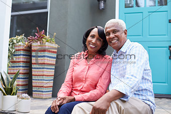 Senior couple sit on steps outside their house, close up