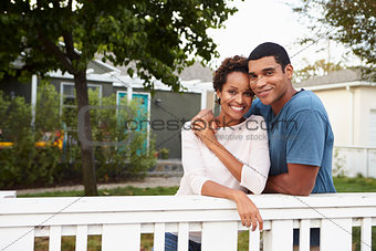Young African American couple embrace outside their house