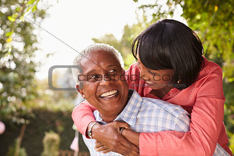 Senior black couple piggyback, looking at each other