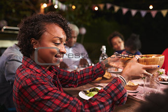 Young black woman passing bowl at a family barbecue