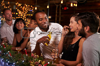 Friends enjoying a Christmas party talk at the bar
