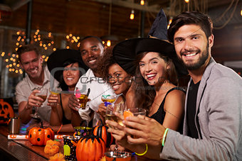 Friends enjoying a Halloween party at a bar look to camera