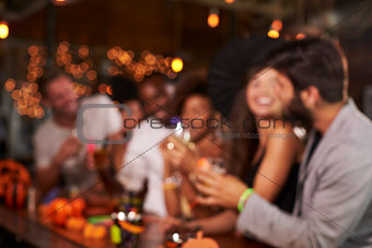 Young adults socialising at a party in a bar, defocussed
