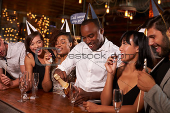 Friends opening champagne at a New YearÕs party at a bar