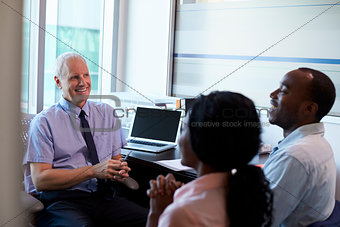 Doctor In Consultation With Couple In Office