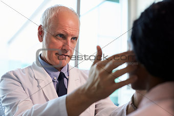 Doctor In White Coat Examining Female Patient In Office