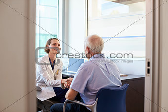 Doctor Shaking Hands With Mature Male Patient In Office