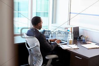 Doctor Working On Laptop At Desk In Office