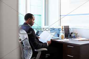 Doctor Working Reading Notes At Desk In Office