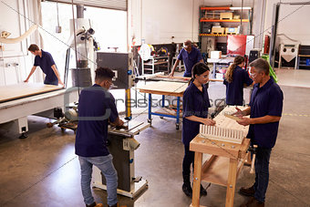 Carpenters Working On Machines In Busy Woodworking Workshop