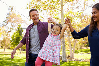 Mixed race couple lifting young daughter in park, close up