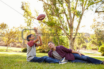 Father and son relax, throwing American football in a park