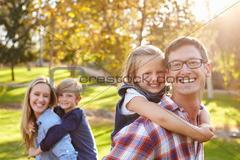 Parents carry their kids piggyback in a park selective focus