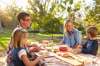 Young white family enjoying a picnic at a table in a park