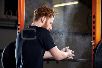 Rear View Of Young Man In Gym Lifting Weights On Barbell
