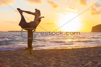 Woman practicing yoga on sea beach at sunset.