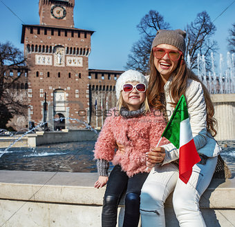 mother and daughter travellers near Sforza Castle showing flag